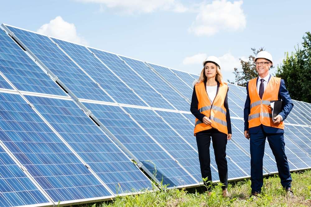 handsome businessman and attractive businesswoman walking near solar energy batteries